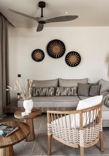 a living room with a couch and a ceiling fan at Lithos Luxury Villa in Archangelos