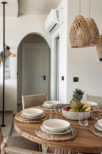 a dining room table with plates and bowls of fruit at Lithos Luxury Villa in Archangelos