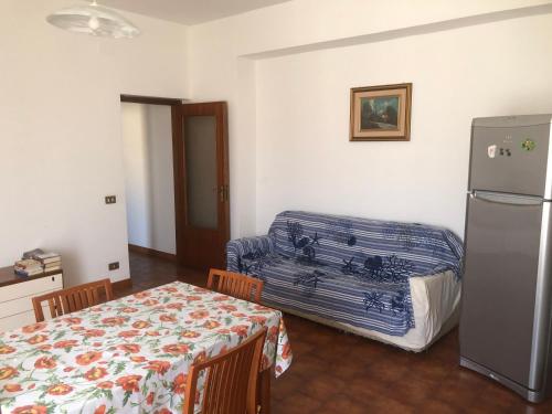 ein Wohnzimmer mit einem Kühlschrank, einem Tisch und einem Kühlschrank in der Unterkunft Appartamento Da Monica in Mirto