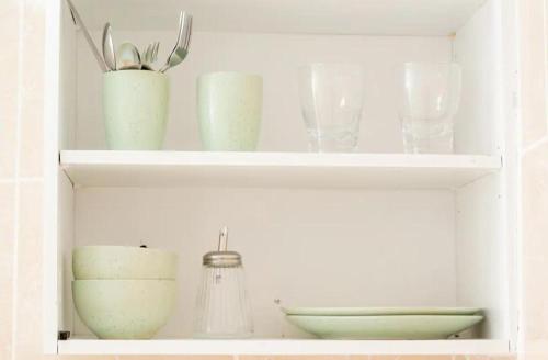 a white shelf with bowls and vases on it at House Corner in San Pedro Sula