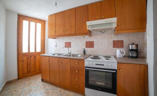 a kitchen with wooden cabinets and a stove and a sink at MinoaHouse 1 bedroom,3 guests,bath tub & patio in Ierápetra