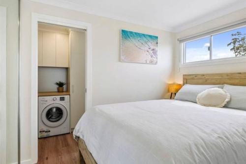 a white bedroom with a bed and a washing machine at Cosy Cabin, Big View ! in Primrose Sands