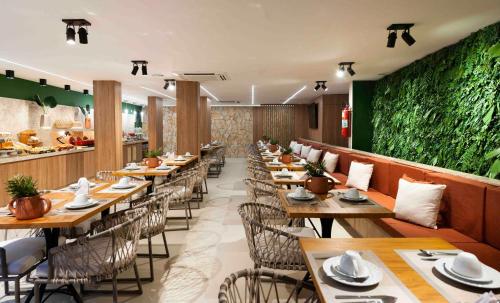 un restaurante con mesas y sillas de madera y una pared verde en Pousada Bahia Tambor, en Morro de São Paulo