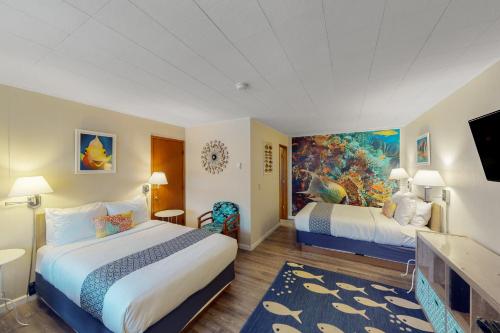 a hotel room with two beds and a painting on the wall at Lamplighter Inn - Tropical Fish Cove and Octopus Encounter in Bandon