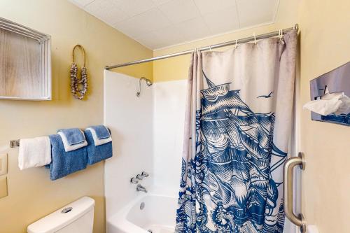 a bathroom with a shower with a blue and white shower curtain at Lamplighter Inn - Tropical Fish Cove and Octopus Encounter in Bandon