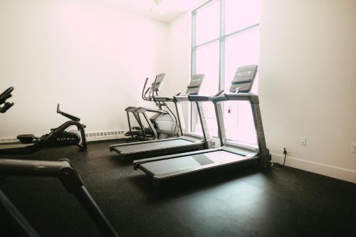 a gym with several tread machines in a room with a window at Chic Cozy Retreat - 2BR - Stunning North End Views in Halifax
