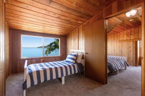 two beds in a room with a window at Skiou Point Beach House in Tulalip