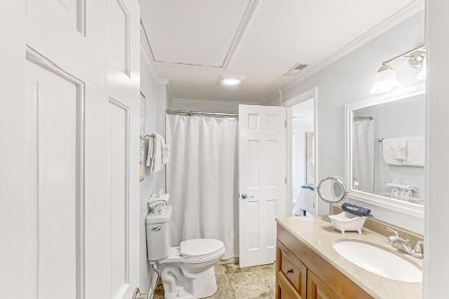 a white bathroom with a toilet and a sink at Lands End in Myrtle Beach
