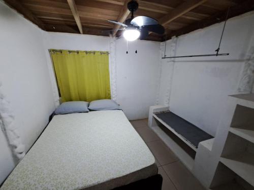 Habitación pequeña con cama y cortina amarilla en Baconao apartment 1 room, en Puerto Viejo