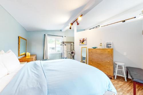 ein Schlafzimmer mit einem weißen Bett und einer Holzkommode in der Unterkunft Evinrude Escape in Coupeville