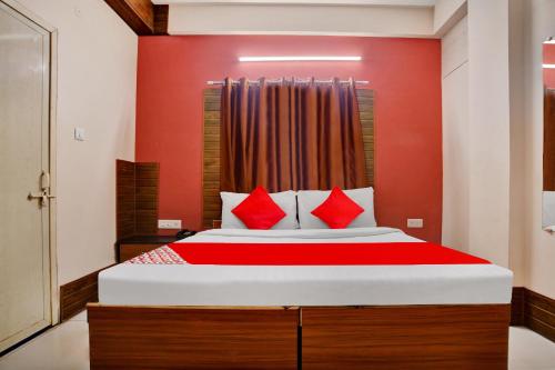 a bedroom with a large bed with red walls at Hotel O Sudipti Resort in Indore