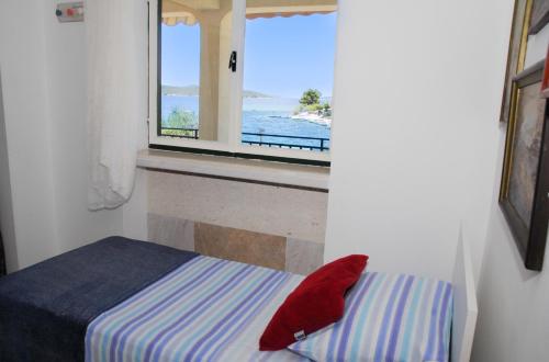 a bedroom with a bed and a window with a view of the ocean at Beachfront Apartment Nikol in Zaboric
