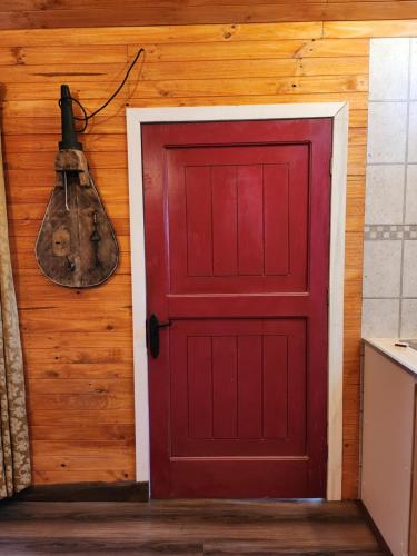 a red door on the side of a wooden wall at Cabañas El Desván in Puente Negro