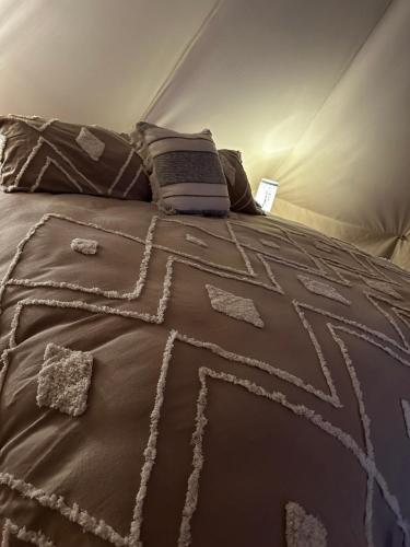 - un lit avec une couette brune et des oreillers dans l'établissement Noonamah Tourist Park, à Noonamah