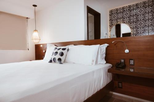 um quarto com uma grande cama branca e um espelho em Nuxká Hotel by Heaven em Telchac Puerto