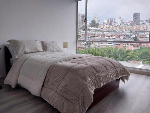 uma cama num quarto branco com uma grande janela em Confortable apartamento em Manizales