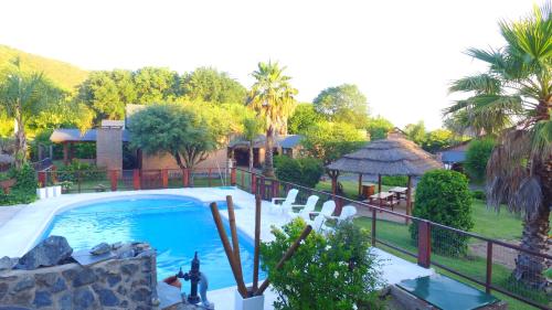 una piscina resort con cenador y palmeras en Cabañas Ranger en Santa Rosa de Calamuchita