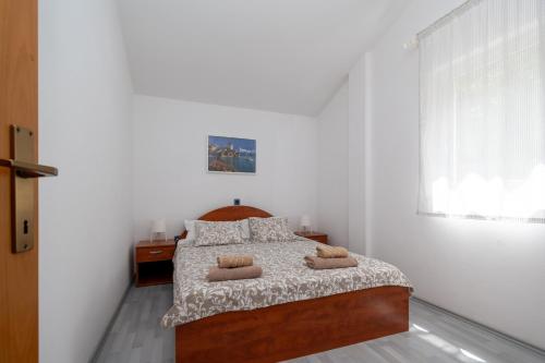 Apartments with a parking space Mandre, Pag - 16836 في ماندري: غرفة نوم بسرير ومخدتين ونافذة