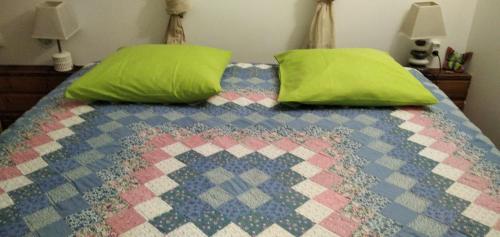 a bed with green pillows and a colorful quilt at Les Pimentiers de Papaye in Saint-Claude