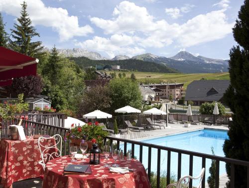 a balcony with a table and a swimming pool at Hotel Christiania in Villard-de-Lans