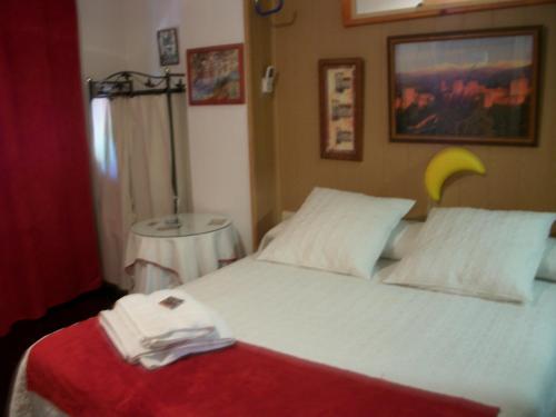 a bedroom with a large white bed with a red blanket at Pensión Moni Albayzin in Granada