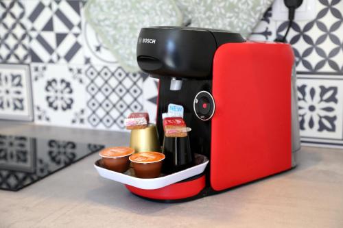una macchinetta del caffè seduta accanto a un contenitore con condimenti di Venus a Saint-Quentin