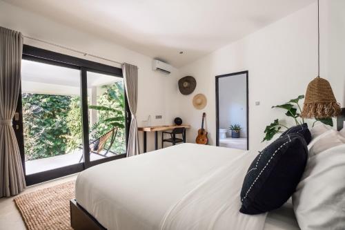 um quarto com uma cama branca e uma grande janela em Villa Kirana - Blissful Oasis with Pool & Jungle-View Garden em Ubud