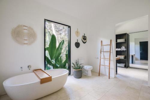 uma casa de banho com uma banheira branca e uma planta em Villa Kirana - Blissful Oasis with Pool & Jungle-View Garden em Ubud