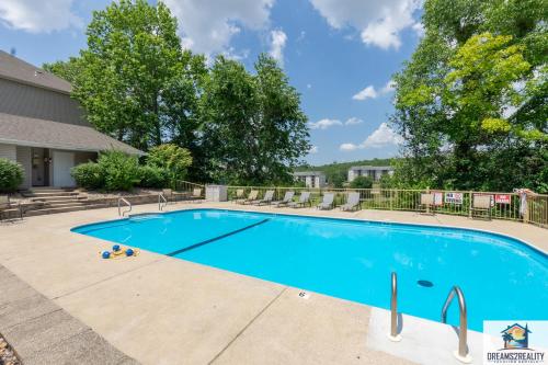 a large blue swimming pool with chairs and trees at 2BR Walk-In Condo - Near the 76 Strip - Pool - FREE TICKETS INCLUDED - CLC-6 in Branson