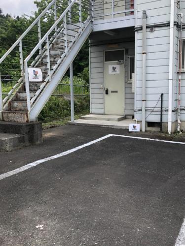 a parking lot in front of a building with a white door at Chichibu Mizuno-stay 水野ステイ最大６名様 in Chichibu