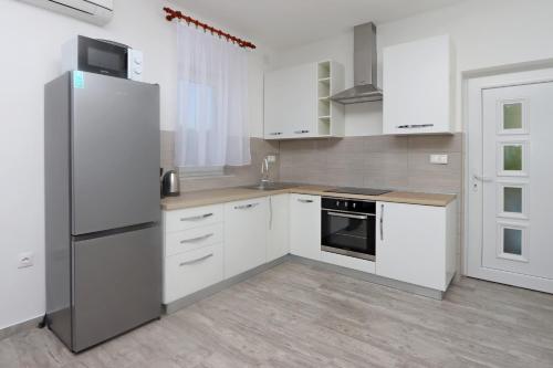 une cuisine avec des armoires blanches et un réfrigérateur en acier inoxydable dans l'établissement Apartments by the sea Potocnica, Pag - 21446, à Potocnica