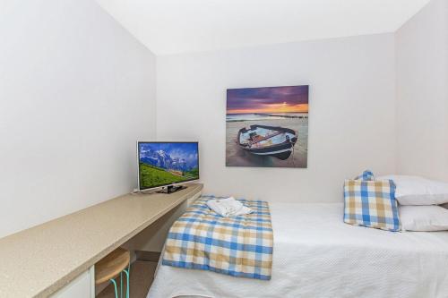 a room with two beds and a desk with a tv at Terrace 4 Kingscliff Oceanfront in Kingscliff