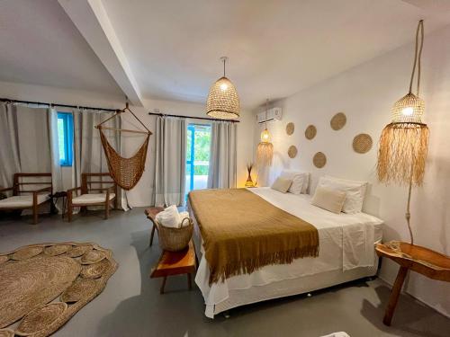 a bedroom with a large bed and a living room at Pousada Caraíva in Caraíva