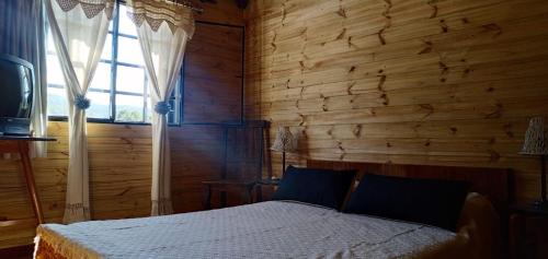 sypialnia z łóżkiem i drewnianą ścianą w obiekcie Cabaña Raices w mieście Unquillo