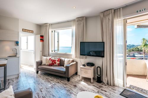 a living room with a couch and a television at Oneroa Central - Coast & Country in Oneroa