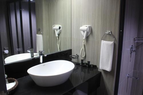 een badkamer met een wastafel en een telefoon aan de muur bij AIM Conference Center in Manilla