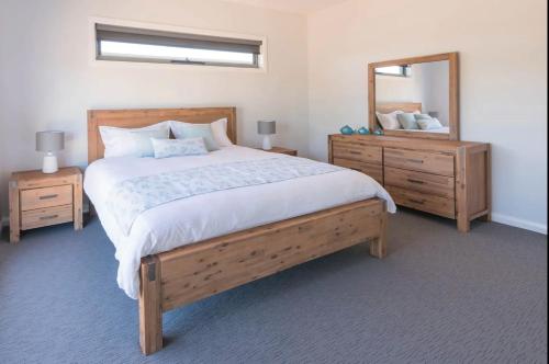 a bedroom with a large bed and a mirror at NEW - Sunrise Waters Holiday House in Mulwala
