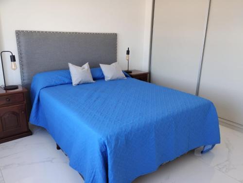 1 dormitorio con 1 cama azul y 2 almohadas en Oportunidad Departamento a Estrenar 2 ambientes hasta 4 personas Mar del plata 12 cuadras del MAR en Mar del Plata