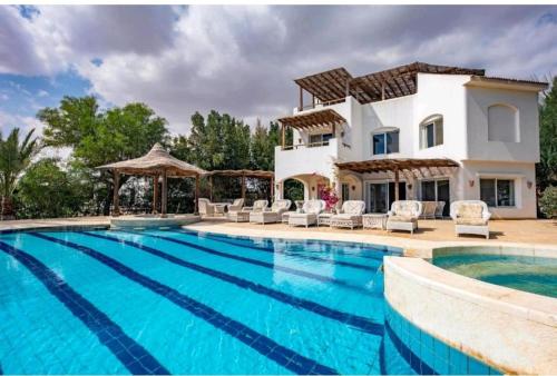 Villa con piscina frente a una casa en الجونه, en Hurghada