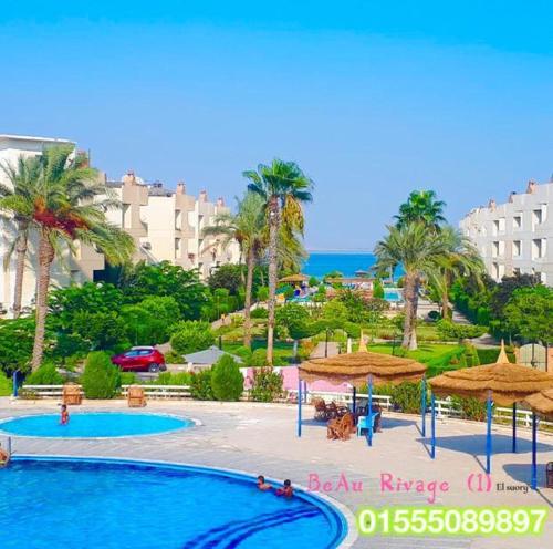 un resort con due piscine e ombrelloni e l'oceano di قرية البوريڤاچ1 a Fayed