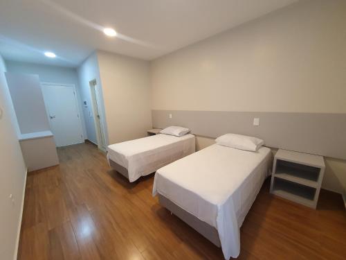 two beds in a small room with wooden floors at Pousada Thermas das Montanhas in Águas de Lindoia