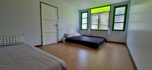 a bedroom with a bed and two windows at Korp View House in Wang Nam Khieo