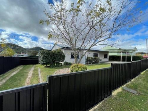 a black fence in front of a house with a tree at LAHOOL GUEST HOUSE JUST A CREEKSIDE STROLL TO TOWN in Stanthorpe