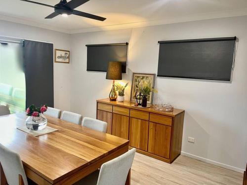 a dining room with a table and a flat screen tv at LAHOOL GUEST HOUSE JUST A CREEKSIDE STROLL TO TOWN in Stanthorpe
