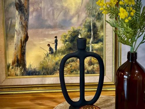 a black bottle sitting next to a vase with a painting at LAHOOL GUEST HOUSE JUST A CREEKSIDE STROLL TO TOWN in Stanthorpe