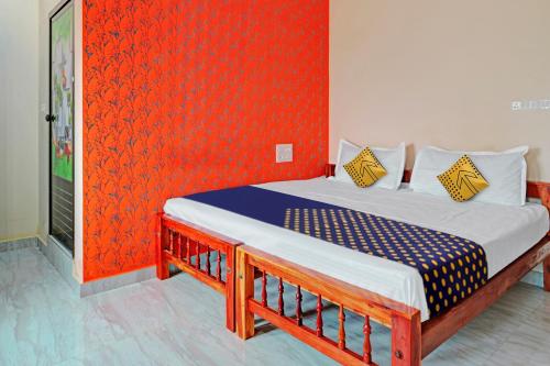 Cama en habitación con pared roja en OYO Hotel Munroe Homestay en Kollam