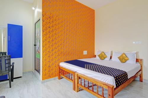 1 dormitorio con 1 cama con pared de color naranja en OYO Hotel Munroe Homestay, en Kollam