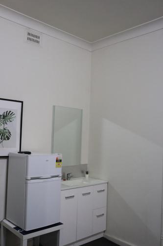 a white kitchen with a refrigerator and a sink at Courthouse Hotel Gunnedah in Gunnedah