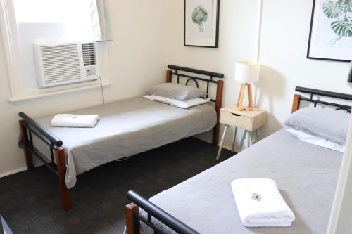 two beds in a small room with a window at Courthouse Hotel Gunnedah in Gunnedah