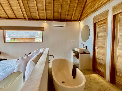 a bathroom with a tub and a bed and a sink at KERTASARI LODGE in Lemonga